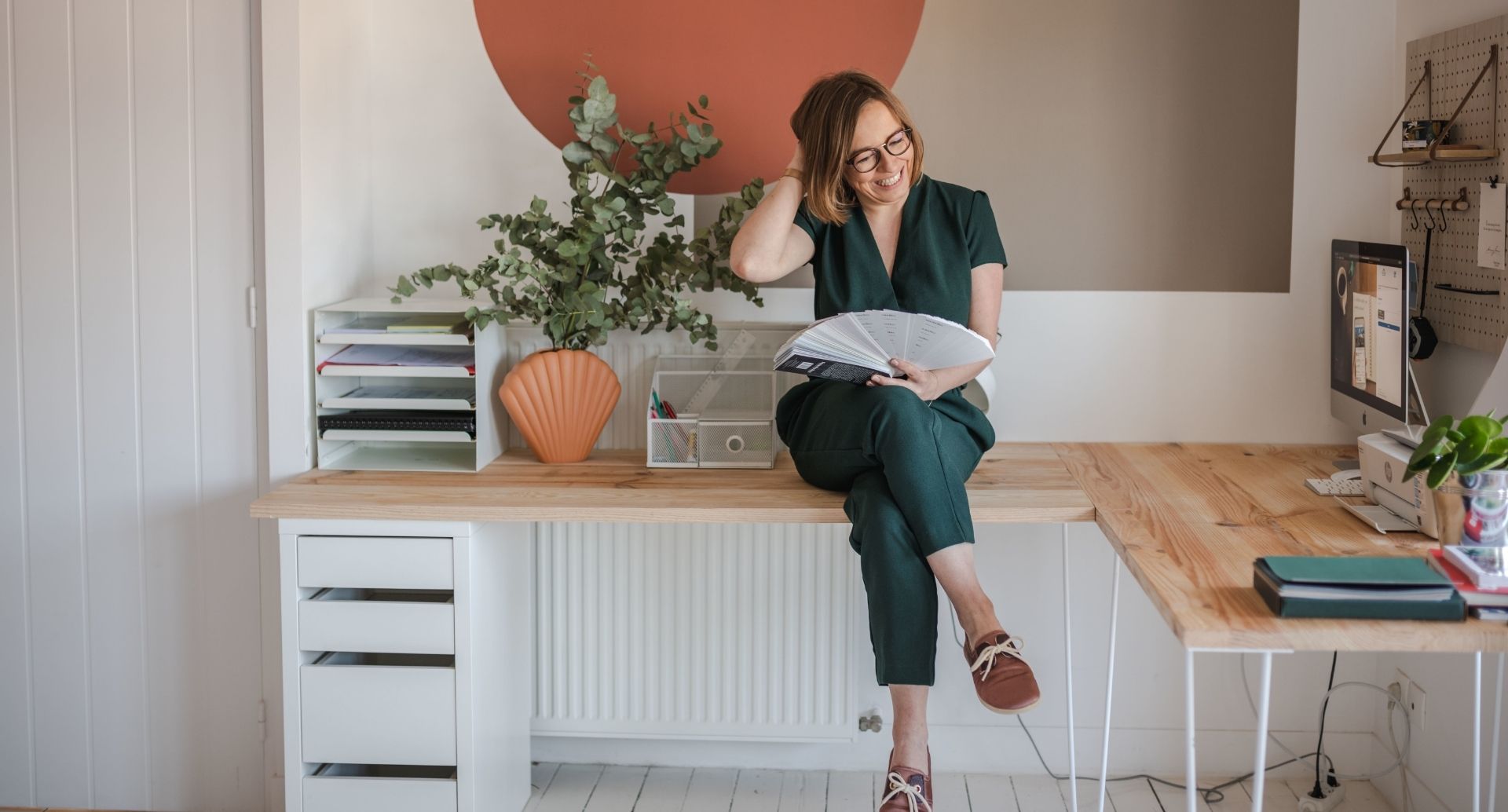 une femme assise sur un bureau tient un nuancier